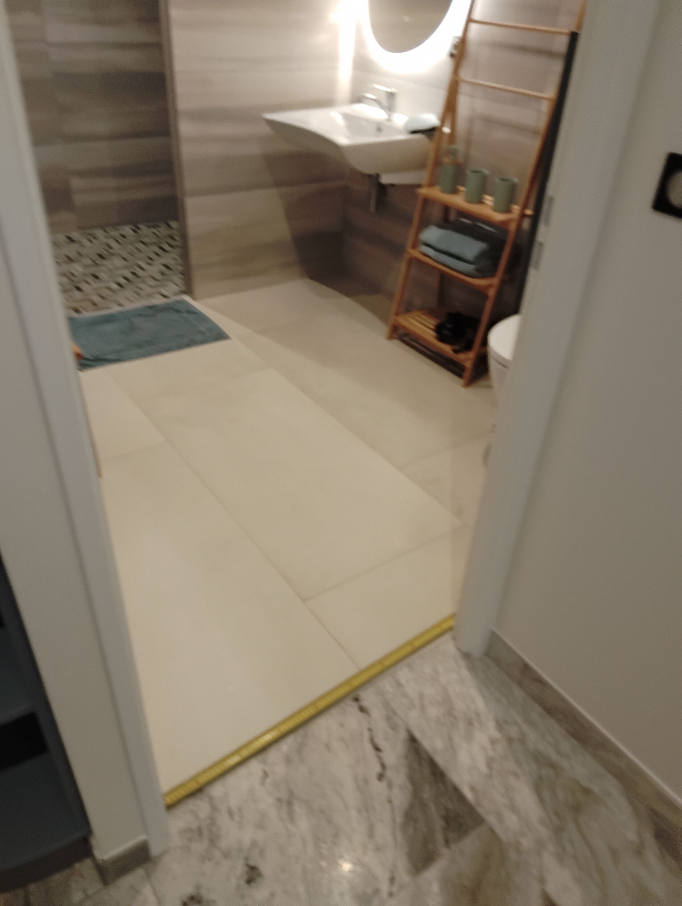 A bathroom with a white sink, a mirror, and a wooden shelf with toiletries.