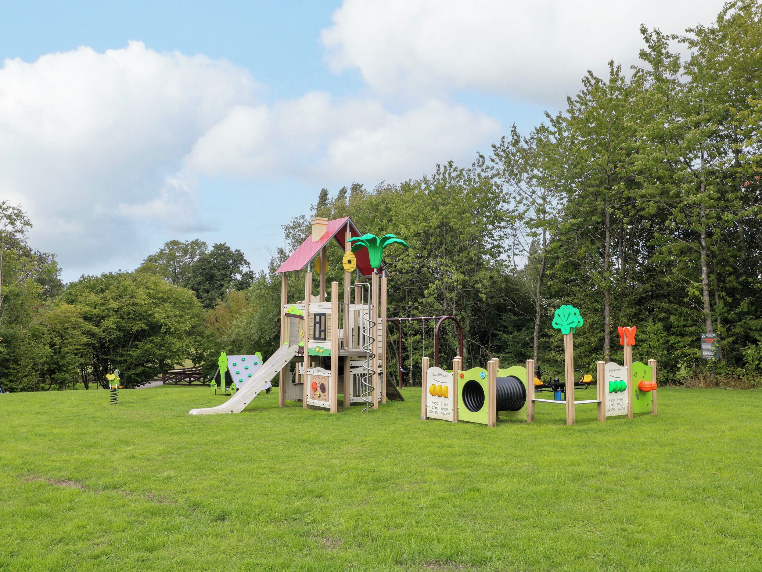 A playground with a slide, climbing structures, and educational play panels.