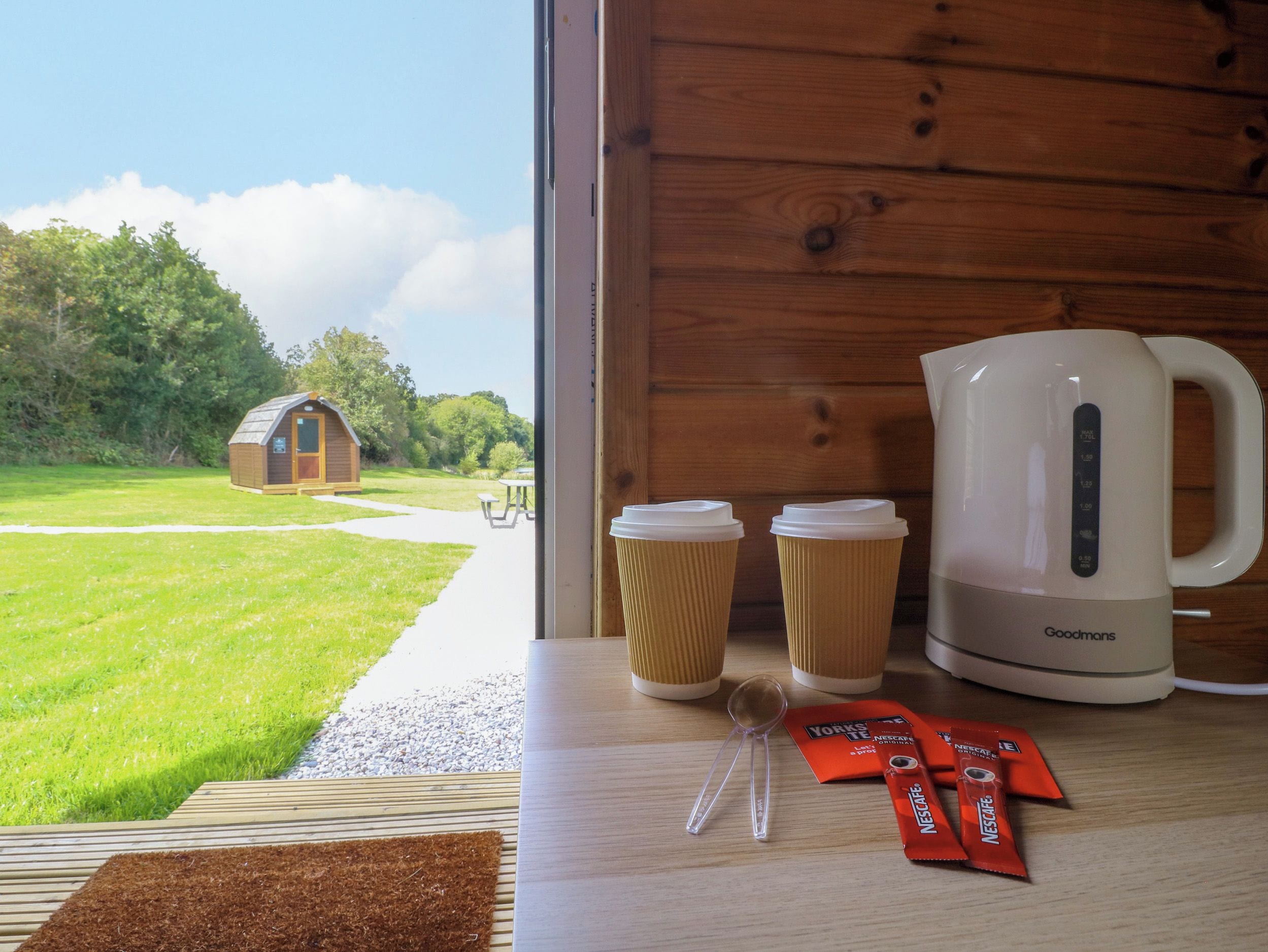 A wooden interior with a view of a grassy area and a small wooden structure outside.