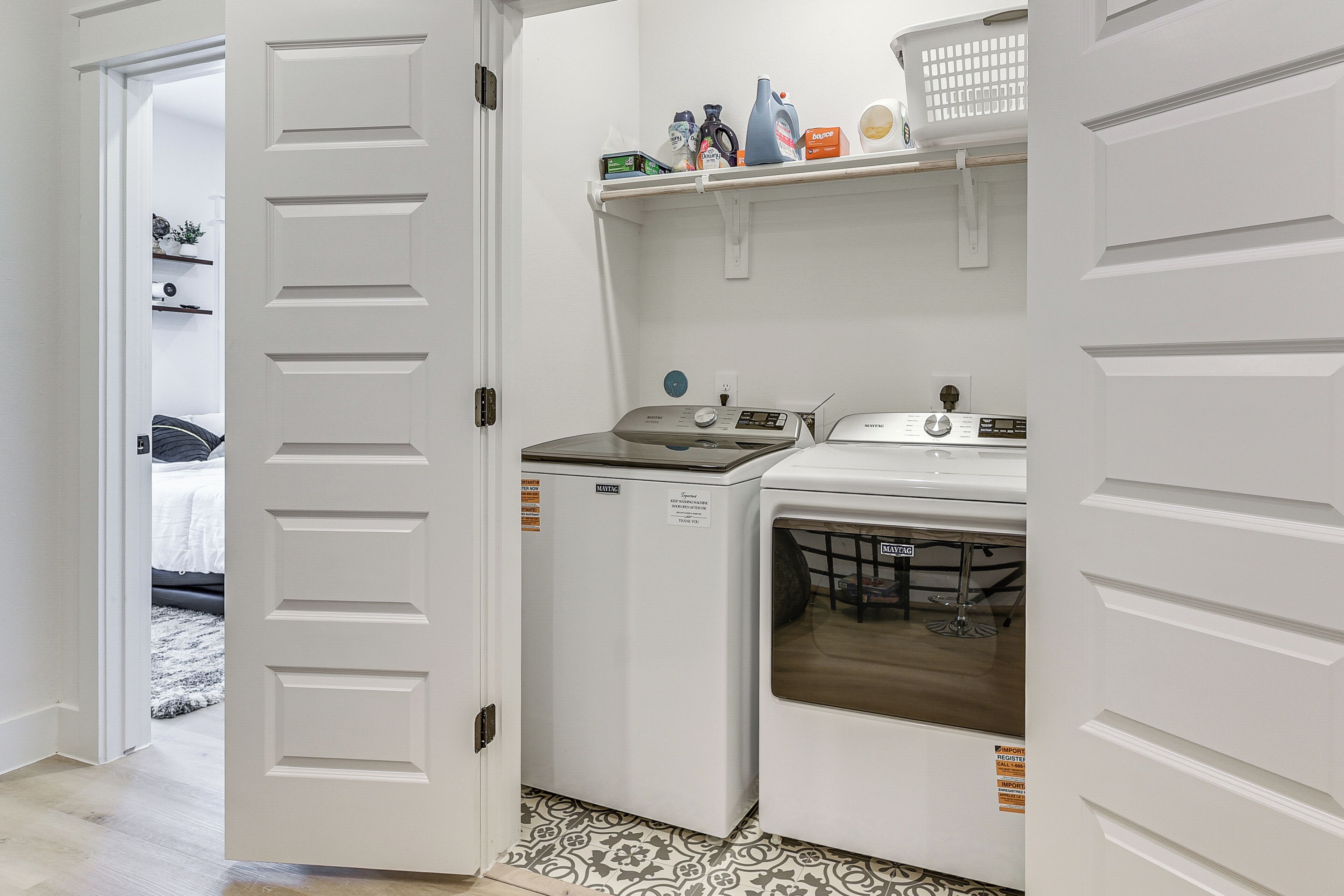 A laundry room with a washing machine, dryer, and shelves with laundry supplies.