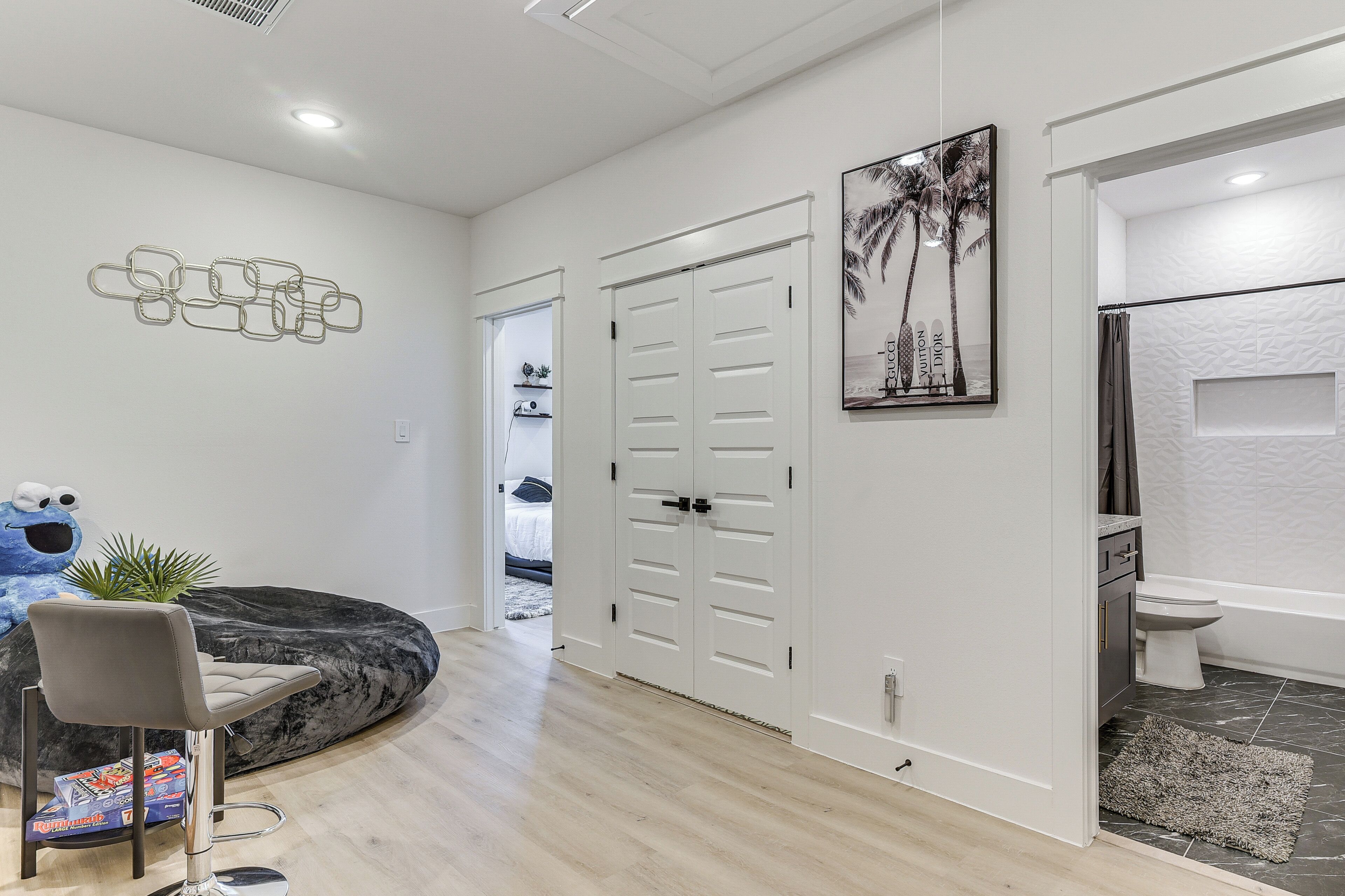 A modern interior with a seating area, a door with a handle, a framed picture, and a toilet.