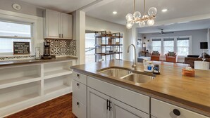 A modern kitchen with a double sink, wooden countertop, and a hanging light fixture.