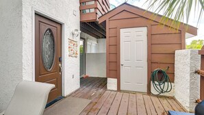 Una terraza de madera con una puerta, un banco y un cobertizo pequeño.