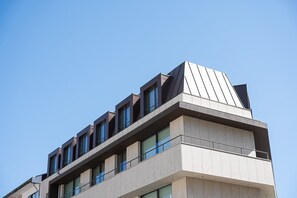 Un edifici modern amb un disseny de teulada geomètric, diversos balcons i grans finestres.