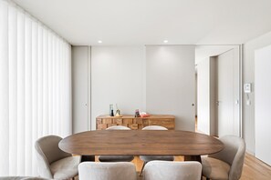 Uma zona de refeições moderna com uma mesa de madeira, quatro cadeiras e um aparador de madeira pequeno com objetos decorativos.
