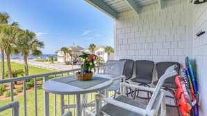 Ein Balkon mit Korbstühlen, einem Tisch mit Pflanze und einem Surfbrettständer.
