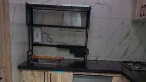 Een keuken met een marmeren spatwand, houten kastjes, een vaatwasser en een betegelde vloer.