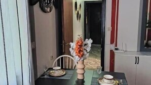 Een eetruimte met een tafel gedekt voor twee personen, een vaas met bloemen en een spiegel aan de muur.