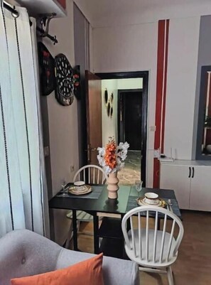 A dining area with a table set for two, a vase with flowers, and a mirror on the wall. - Le Secret | Elegance & Comfort in the Heart of Rabat (Rabat)