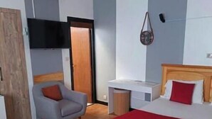 Een slaapkamer met een bed, een stoel, een bureau en een televisie.