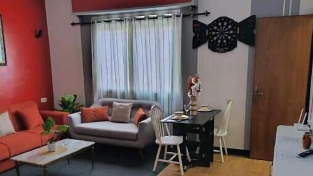 Een woonkamer met een bank, fauteuil, eettafel en een decoratief wandobject.