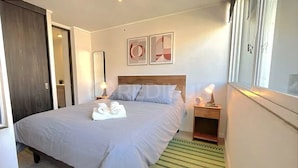 A hotel room with a bed, two bedside tables, a window, and a door. - Rbk Wifi Smart TV Cowork y Terraza verde (Santiago)