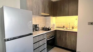A compact kitchen with a refrigerator, stove, and sink. - Rbk Wifi Smart TV Cowork y Terraza verde (Santiago)
