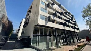 A modern building with multiple floors, large windows, and a flat roof. - Rbk Wifi Smart TV Cowork y Terraza verde (Santiago)