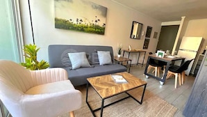A modern living room with a grey sofa, a wooden coffee table, a grey armchair, and a dining area with a small table and chairs. - Rbk Wifi Smart TV Cowork y Terraza verde (Santiago)
