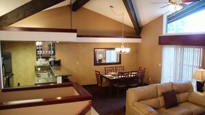 Un coin repas avec une table et des chaises, une cuisine avec un comptoir et des appareils électroménagers, et un salon avec un canapé.