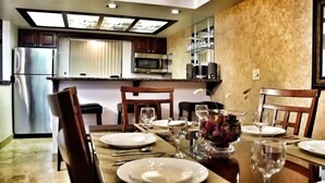Un coin repas avec une table dressée pour quatre personnes, comprenant des assiettes, des verres et des couverts.