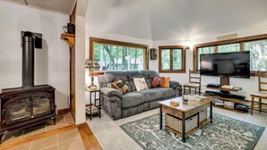 Una sala de estar acogedora con chimenea, un sofá, un televisor y una mesa de centro.