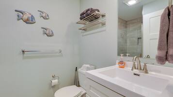 Uma casa de banho moderna com uma sanita, uma pia branca e um porta-toalhas.
