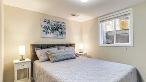 A bedroom with a bed, two bedside tables, a nightstand, a window, and a wall-mounted painting. - Walk to Parks & Dining! Meridian Home w/ Patio (Meridian)