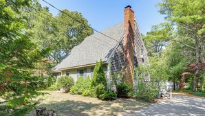 A single-story house with a steeply pitched roof, a brick chimney, and a front porch. - Classic Cape House 5M to Nauset Beach (Orleans)