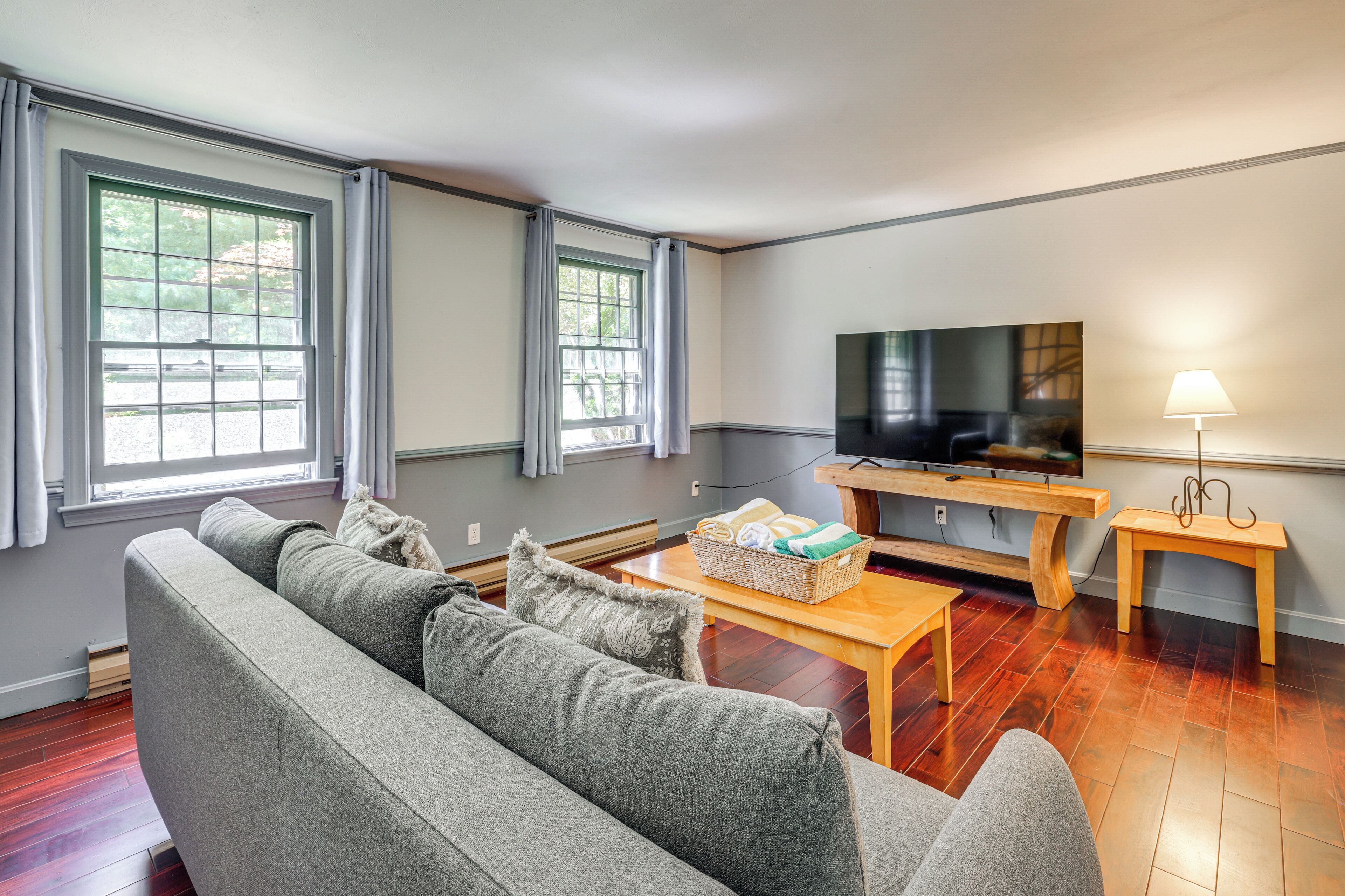 Una sala de estar con un sofá, una televisión, una mesa de centro de madera y una lámpara.