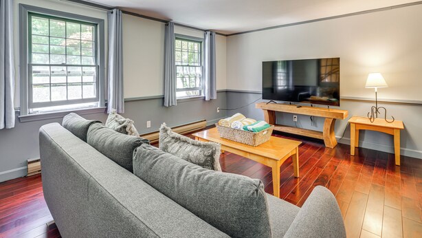 A living room with a sofa, a television, a wooden coffee table, and a lamp. - Classic Cape House 5M to Nauset Beach (Orleans)
