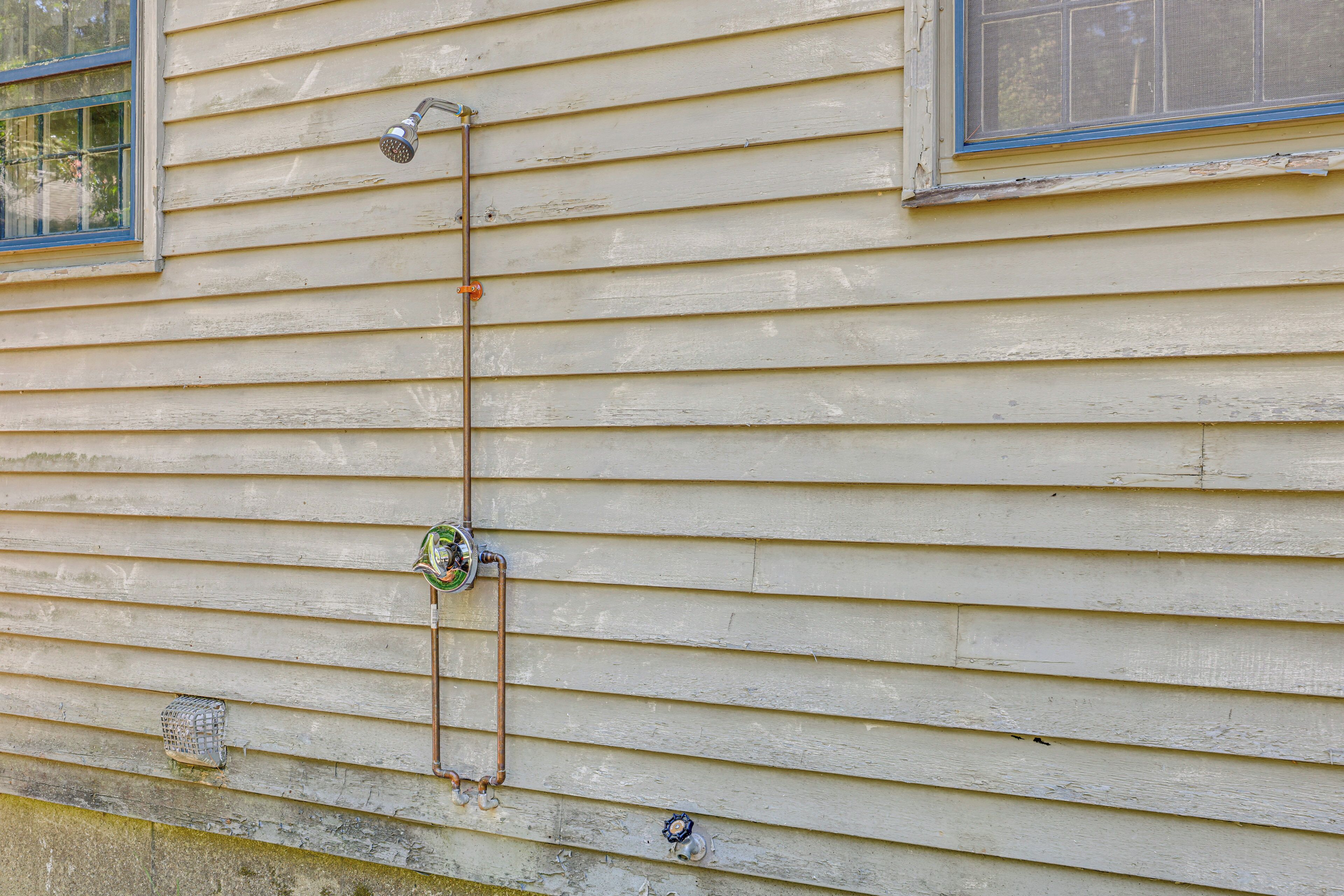 A house with exterior plumbing, a window, and a door.
