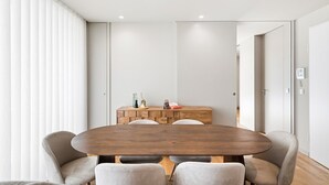 Un espace repas moderne avec une table en bois, quatre chaises et un petit buffet en bois agrémenté d’objets décoratifs.