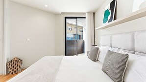 Une chambre d’hôtel moderne avec un grand lit, une vue sur l’extérieur et un balcon.