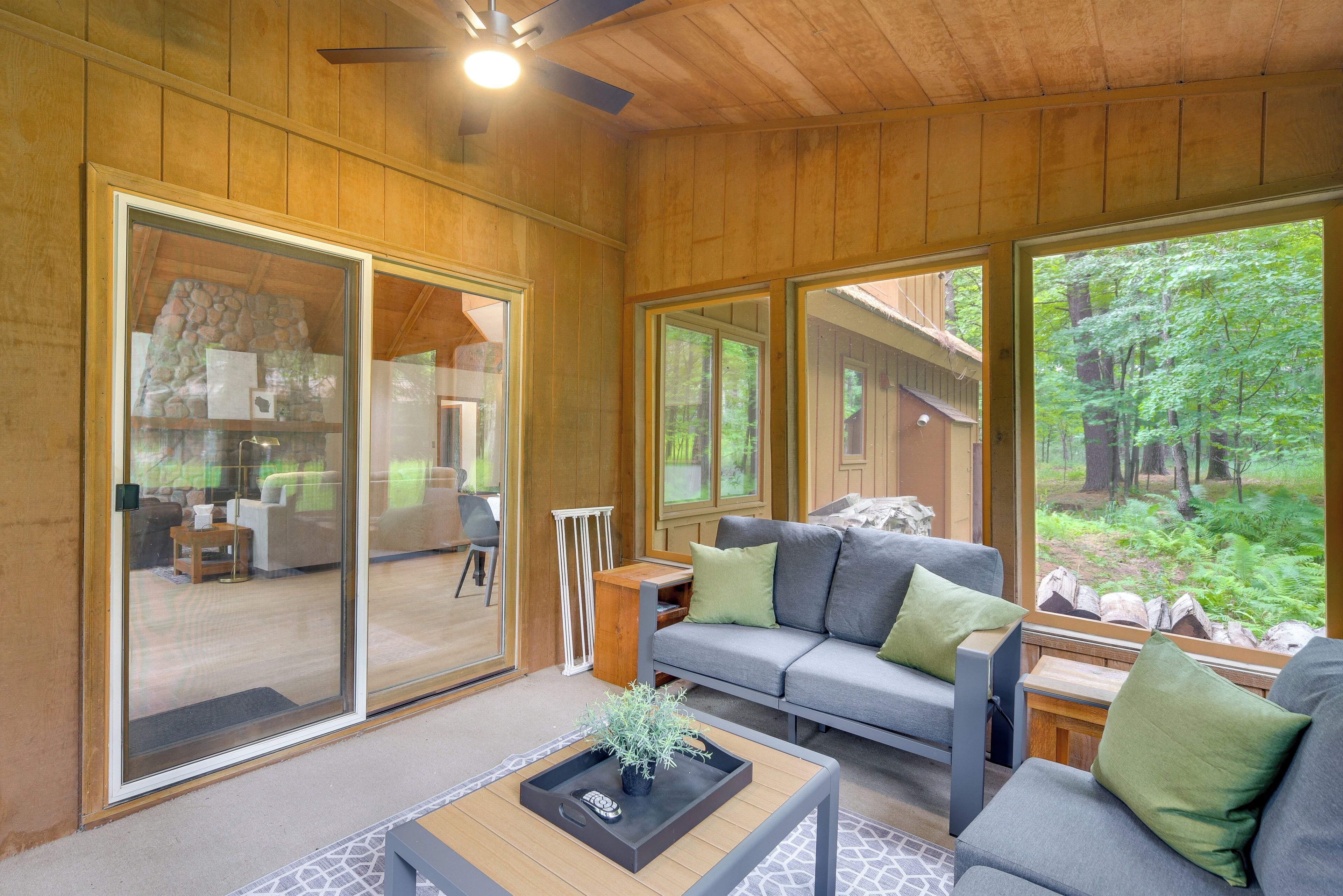 A modern interior with a wooden ceiling, large sliding glass doors, a grey sofa with green cushions, and a small table with a tray.