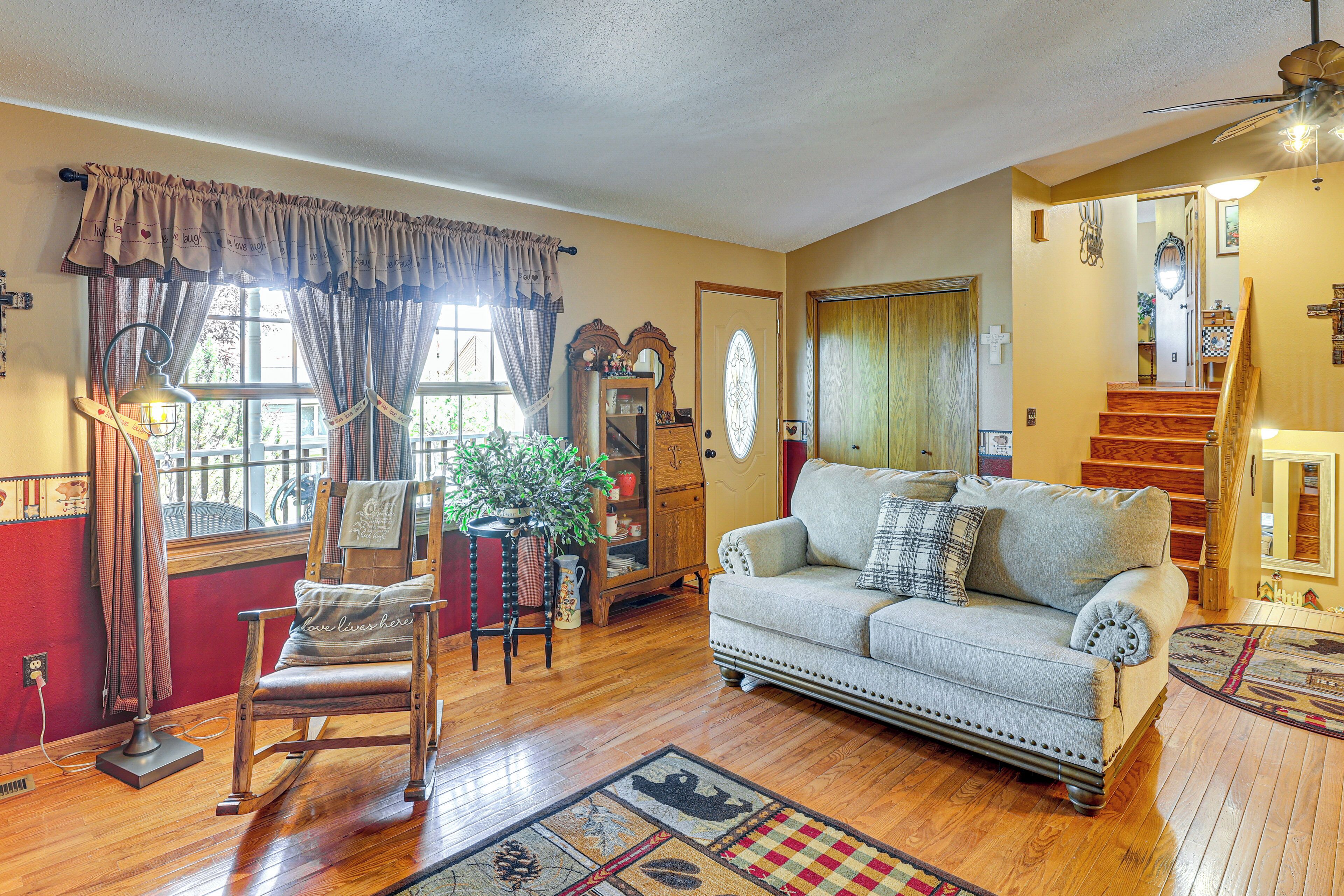 A living room with a rocking chair, a sofa, a wooden cabinet, and a staircase leading to another level.