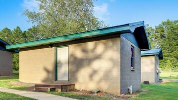 A small, single-story building with a green roof, a door, and a window.