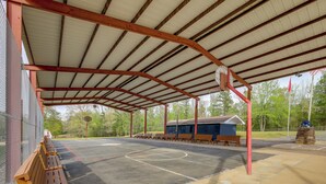 A covered basketball court with benches, a small building, and a stone monument. - Studio w/ Greers Ferry Lake Access & Resort Perks! (Clinton)