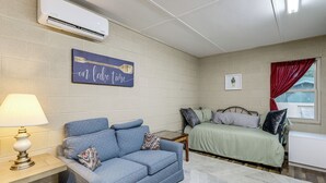 A room with a blue sofa, a bed, a bedside table, and an air conditioning unit. - Studio w/ Greers Ferry Lake Access & Resort Perks! (Clinton)