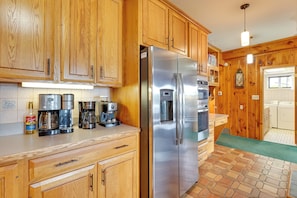 A kitchen with wooden cabinets, stainless steel appliances, and a coffee maker. - Stunning Lakefront Camps, Escape/ Explore Together (Lake George)
