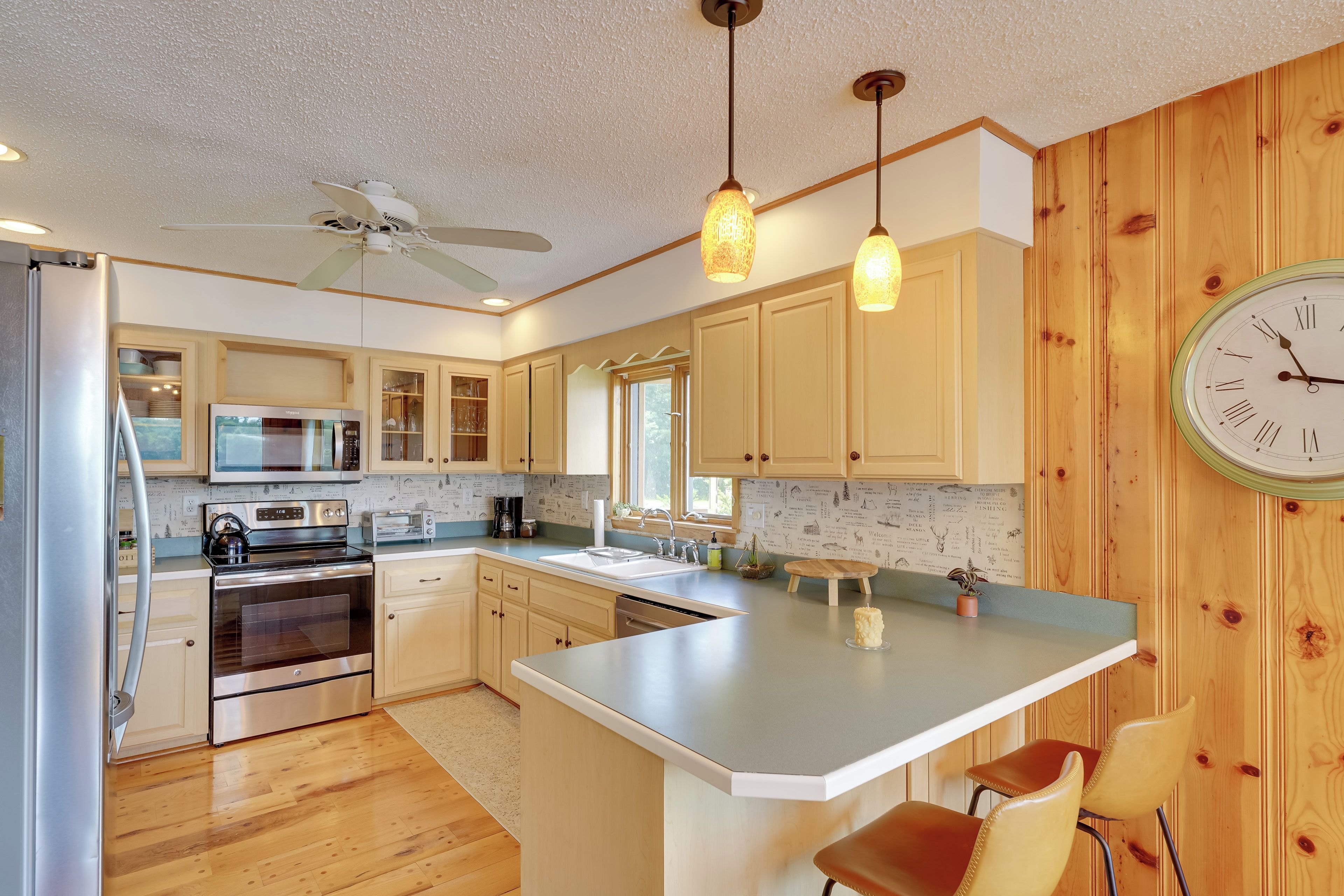 Una cocina moderna con paneles de madera, electrodomésticos de acero inoxidable e iluminación colgante.