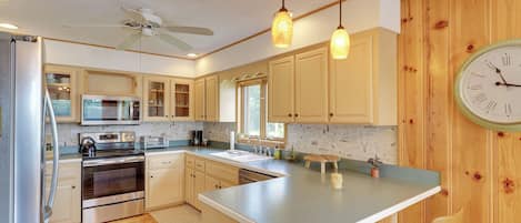 Una cocina moderna con paneles de madera, electrodomésticos de acero inoxidable e iluminación colgante.