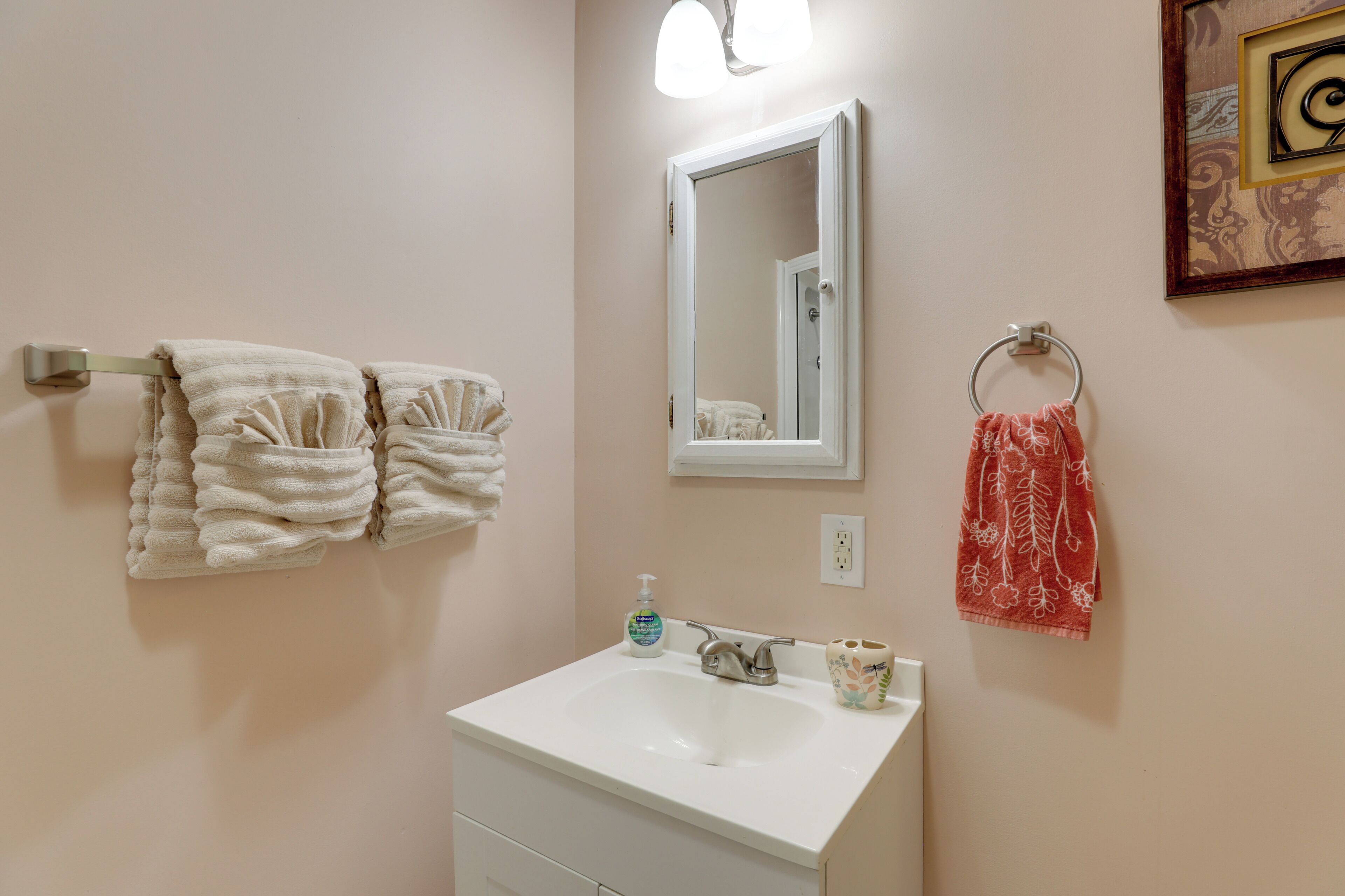 A bathroom with a sink, mirror, towel rack, and a framed picture on the wall.
