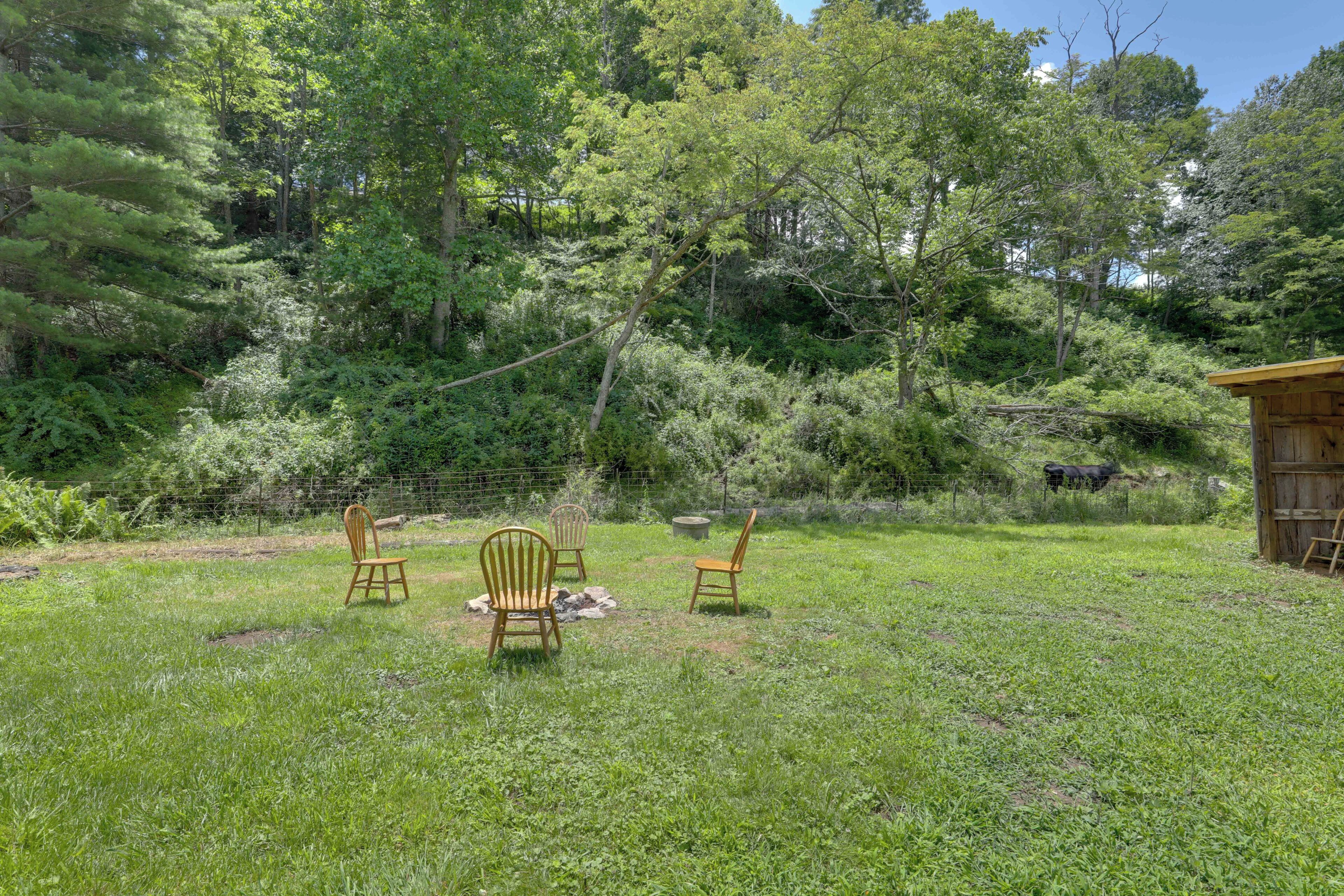 A grassy outdoor area with three wooden chairs and a small wooden structure.