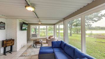 A covered patio with a blue sofa, a small table, and a TV.