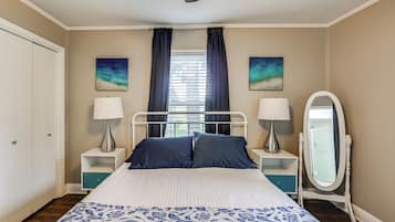 A bedroom with a bed, two nightstands, a dresser, a mirror, and artwork on the walls.