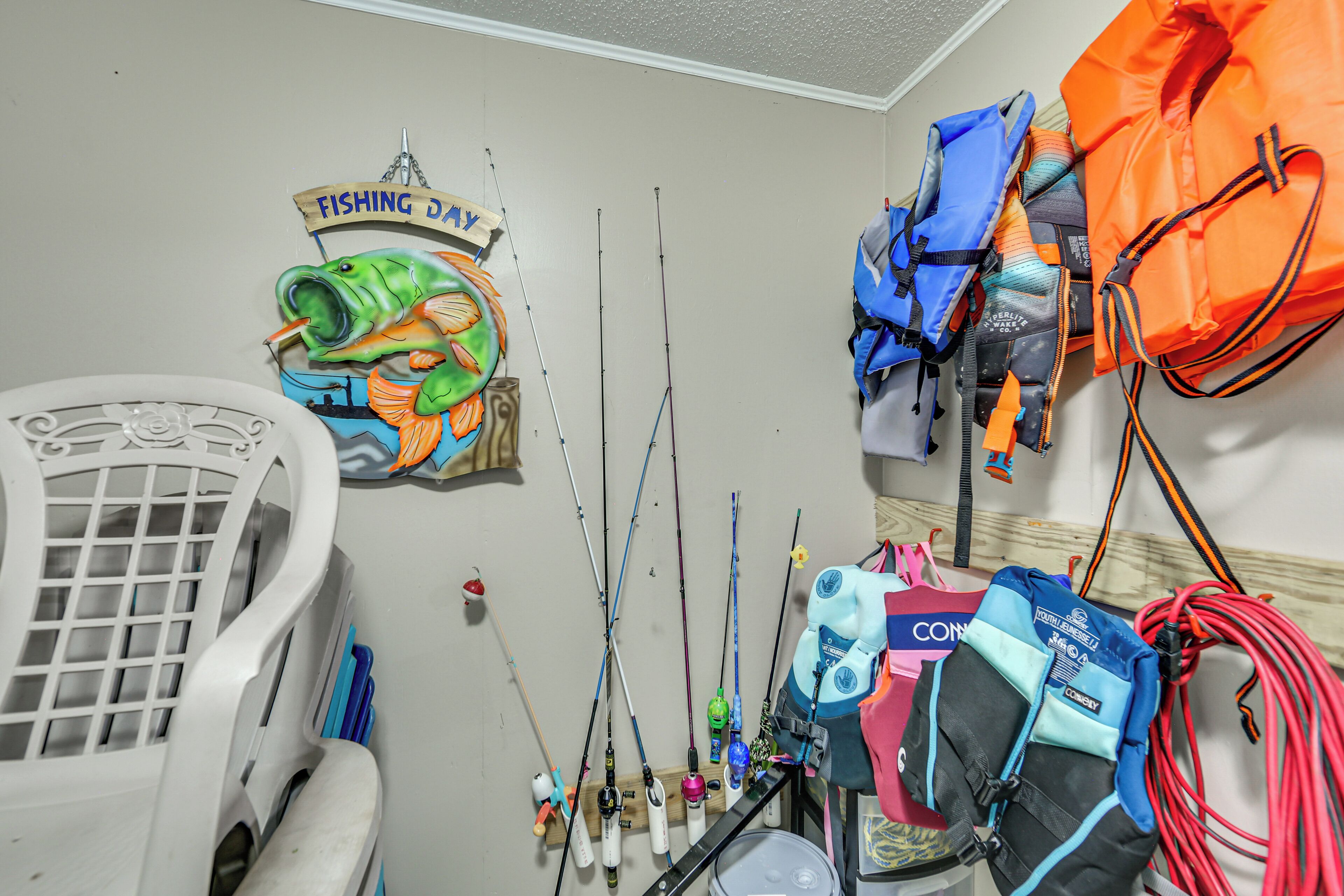 A room with fishing rods, a chair, and various bags and equipment.