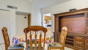A dining area with a table covered by a colorful tablecloth, wooden chairs, and a wooden cabinet with a decorative top. - Great for Couples & Duos: Suite Outside El Paso (El Paso)