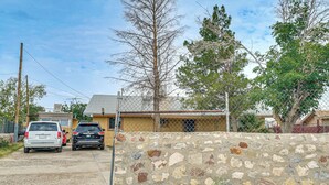 A residential street with two parked cars, a stone wall, and houses in the background. - Great for Couples & Duos: Suite Outside El Paso (El Paso)