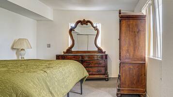 A bedroom with a bed, a dresser, a mirror, and a lamp.