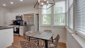 A modern kitchen with white cabinetry, stainless steel appliances, and a dining area with a wooden table and chairs. - Near Centennial Park! Fayetteville Extended Stay (Fayetteville)