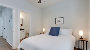 A bedroom with a bed, bedside tables, a nightstand, a mirror, a door, and a hallway. - Near Centennial Park! Fayetteville Extended Stay (Fayetteville)