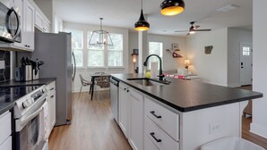 A modern kitchen with a large island, stainless steel appliances, pendant lighting, and a dining area with natural light. - Near Centennial Park! Fayetteville Extended Stay (Fayetteville)