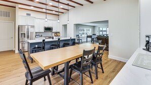 Una cocina moderna con gabinetes blancos, electrodomésticos de acero inoxidable y una mesa de comedor de madera con sillas.
